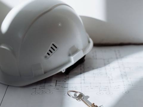 Hard hat and a key resting on blueprints