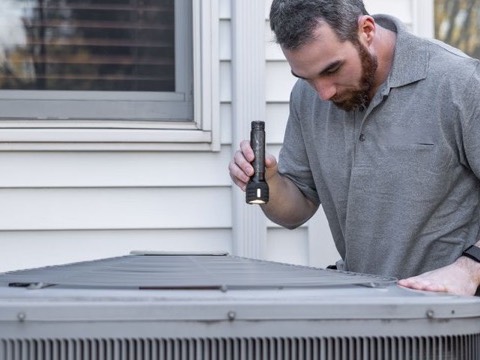 HVAC technician inspecting an outdoor unit