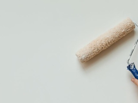 Paint roller mid-stroke on a wall